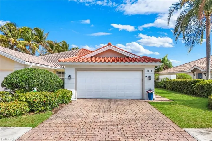 Mediterranean / spanish home featuring a tiled roof, decorative driveway, stucco siding, and a front lawn