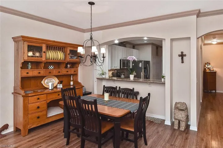 Dining area with elegant crown molding, chandelier, and passthrough to the kitchen.