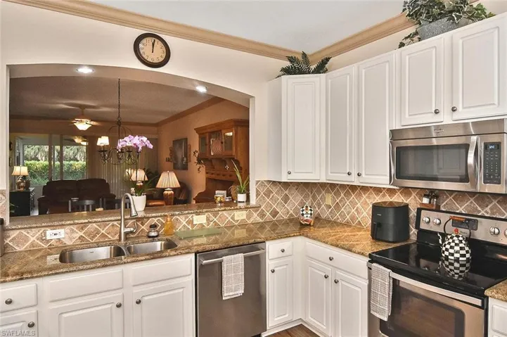 Kitchen has new LVP flooring and a large expanse of granite countertops and coordinating stone tile backsplash.