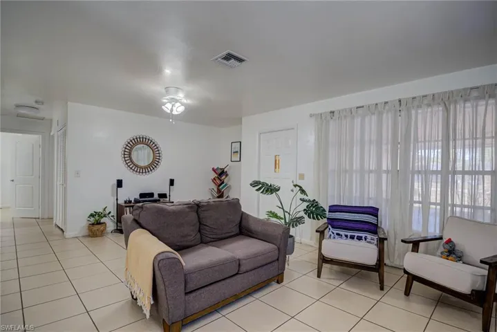 Living area with a ceiling fan, baseboards, visible vents, and light tile patterned floors