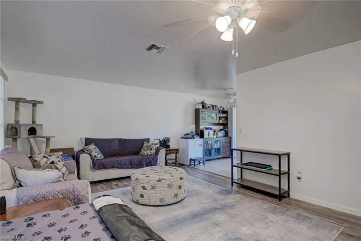 Living room with visible vents, a ceiling fan, baseboards, and wood finished floors