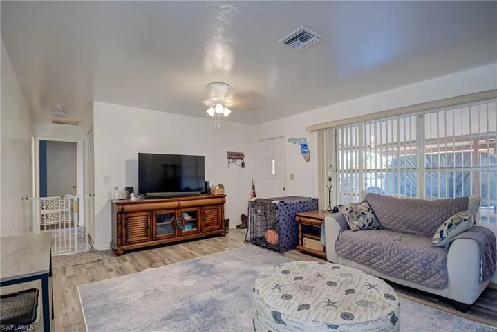 Living room with a ceiling fan, baseboards, visible vents, and light wood-style flooring