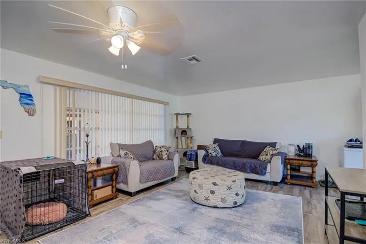 Living area with visible vents, a ceiling fan, and wood finished floors