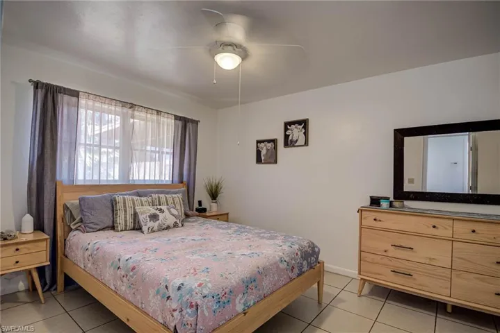 Bedroom with light tile patterned flooring, baseboards, and a ceiling fan