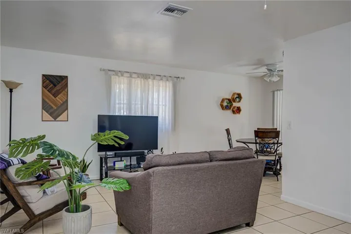 Living room featuring light tile patterned floors, baseboards, ceiling fan, and visible vents
