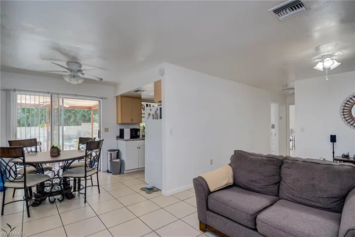 Living room featuring light tile patterned flooring, ceiling fan, visible vents, and baseboards