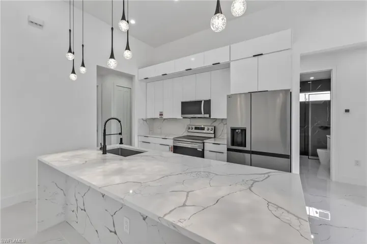 Spacious kitchen island featuring a waterfall-edge countertop and integrated sink with a matte black faucet