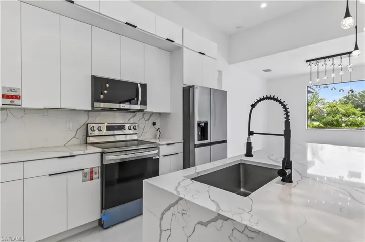 Modern kitchen featuring white flat-panel cabinetry and stainless steel appliances
