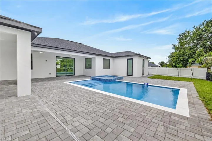 Expansive paver patio with a rectangular swimming pool and integrated spa