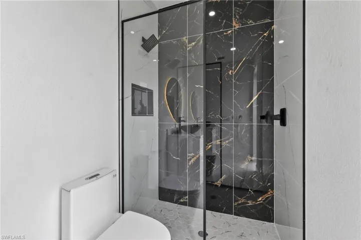 Contemporary shower enclosure featuring black-framed glass and black marble-effect wall tiling with gold veining