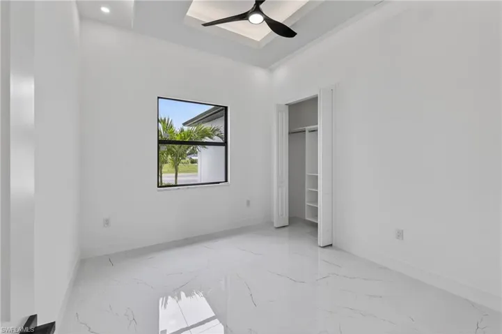 Bright room featuring white walls and large format marble-look tile flooring