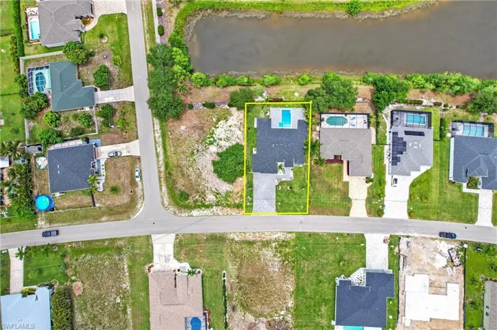Aerial view showcasing a residential property with a dark shingle roof and a swimming pool