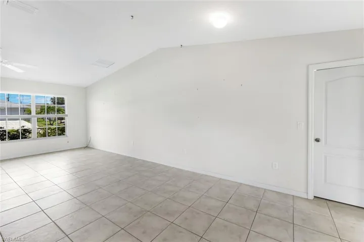 Spare room with ceiling fan, light tile patterned floors, and lofted ceiling