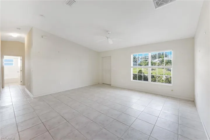 Unfurnished room featuring a ceiling fan, light tile patterned flooring, and vaulted ceiling