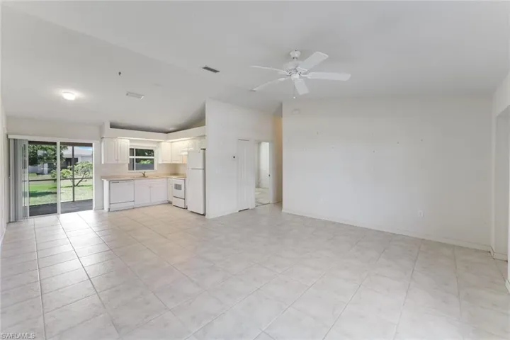 Unfurnished living room featuring vaulted ceiling, a ceiling fan, and light tile patterned floors