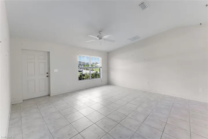 Unfurnished room featuring a ceiling fan, light tile patterned floors, and vaulted ceiling