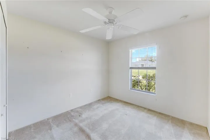 Carpeted spare room with baseboards and a ceiling fan