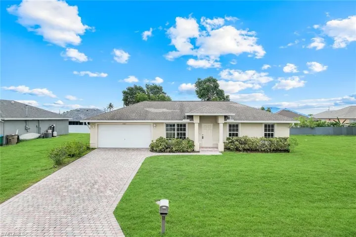 Ranch-style house featuring stucco siding, decorative driveway, an attached garage, and a front lawn