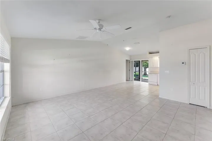 Empty room featuring light tile patterned floors, a ceiling fan, and lofted ceiling