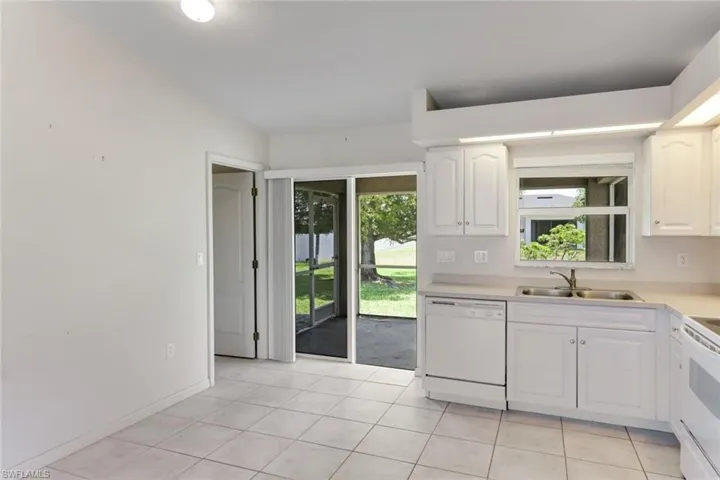 Kitchen with white appliances, white cabinets, light countertops, and light tile patterned flooring