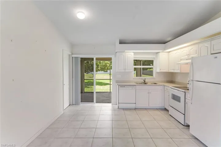 Kitchen with white appliances, healthy amount of natural light, white cabinets, and light countertops