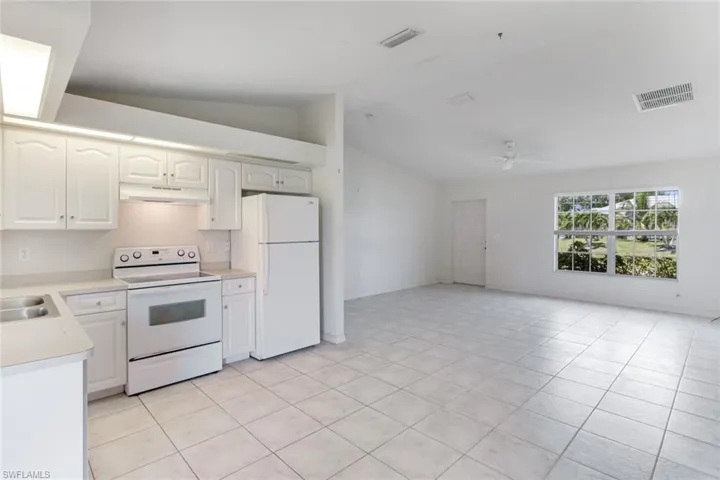 Kitchen featuring white appliances, lofted ceiling, light countertops, ceiling fan, and under cabinet range hood