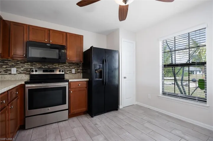 Kitchen with black appliances, light countertops, and a ceiling fan