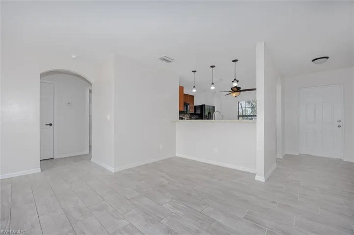 Unfurnished living room with arched walkways, wood tiled floors, and ceiling fan