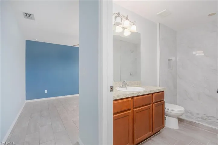 Bathroom with vanity, a marble finish shower, and wood finish floors