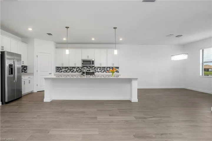 Kitchen includes custom backsplash, over and under cabinet lighting, oversized island, walk-in pantry, and stainless steel appliances.