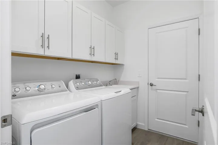 Laundry room features utility sink and additional upper cabinets for extra storage.