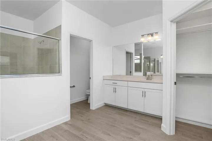 Primary bath with dual vanities/sinks, two walk-in closets with custom built in shelving, and large walk-in shower.
