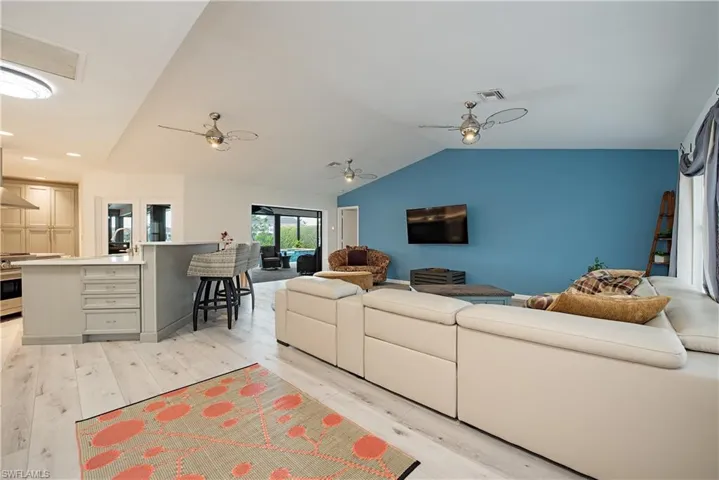Living room featuring light wood-type flooring, vaulted ceiling, and ceiling fan