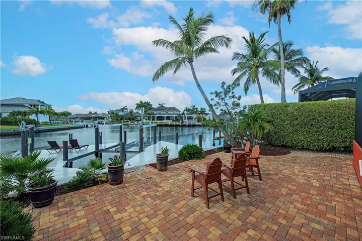 View of patio with boat lift, a dock, a water view, and a residential view