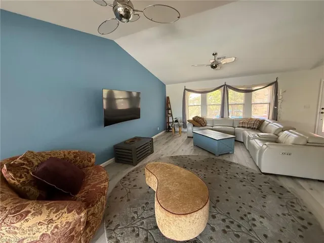 Living area featuring vaulted ceiling, wood finished floors, and a ceiling fan