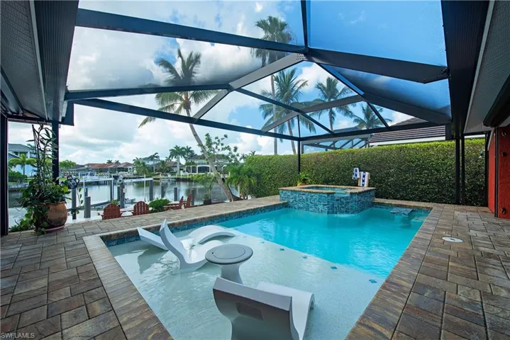 View of pool featuring a water view, a patio, a pool with connected hot tub, and boat lift