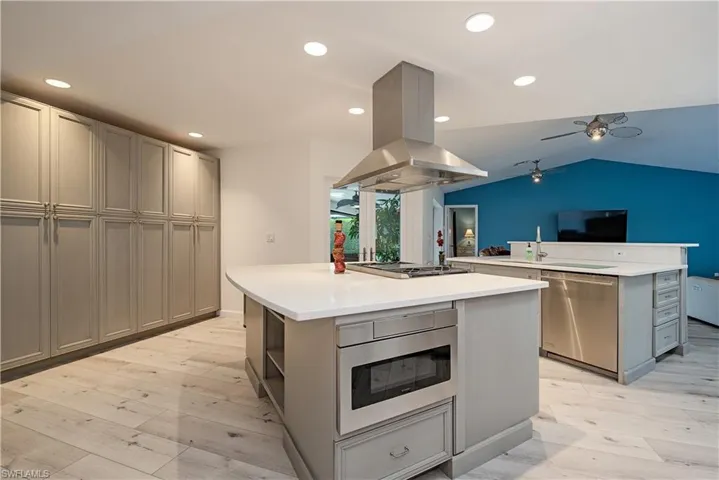 Kitchen with light wood-type flooring, gray cabinets, a center island, island exhaust hood, and recessed lighting