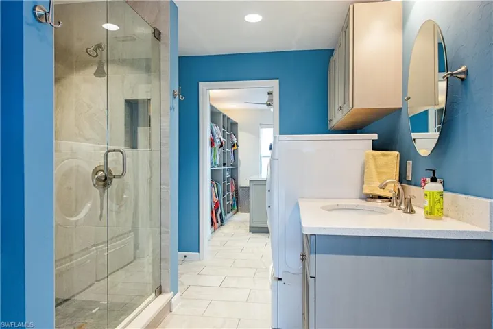 Bathroom featuring a stall shower, vanity, ceiling fan, washer / clothes dryer, and a spacious closet