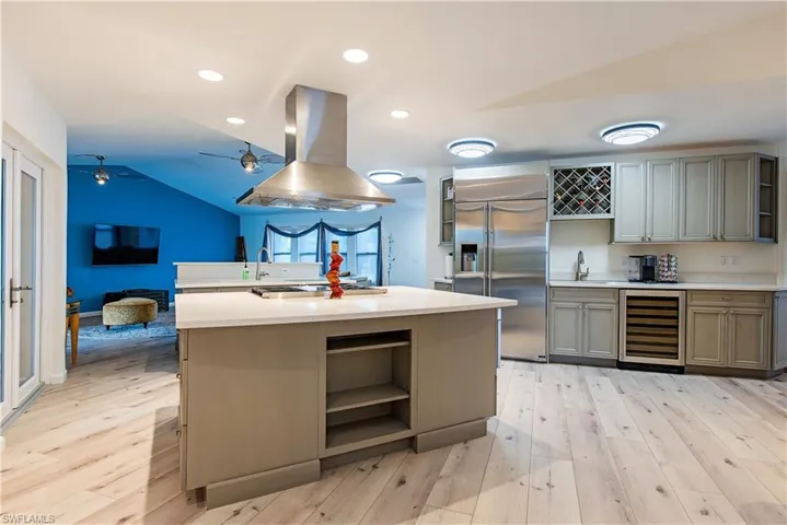Kitchen featuring open shelves, gray cabinets, light countertops, island range hood, and stainless steel built in fridge