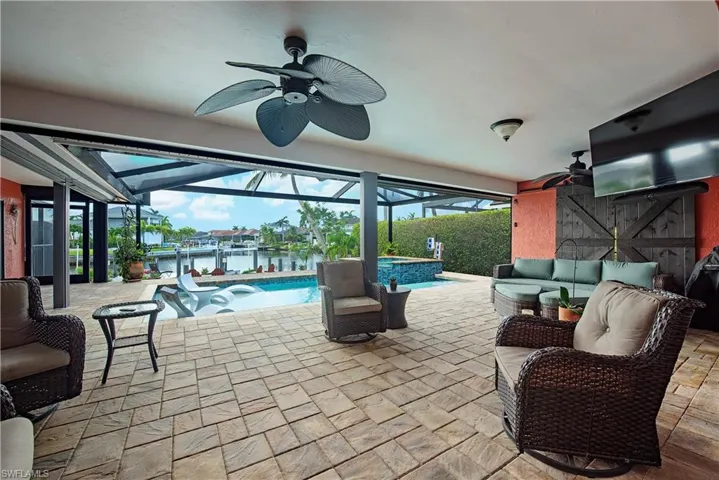 View of patio featuring ceiling fan, an outdoor living space, glass enclosure, and a pool with connected hot tub