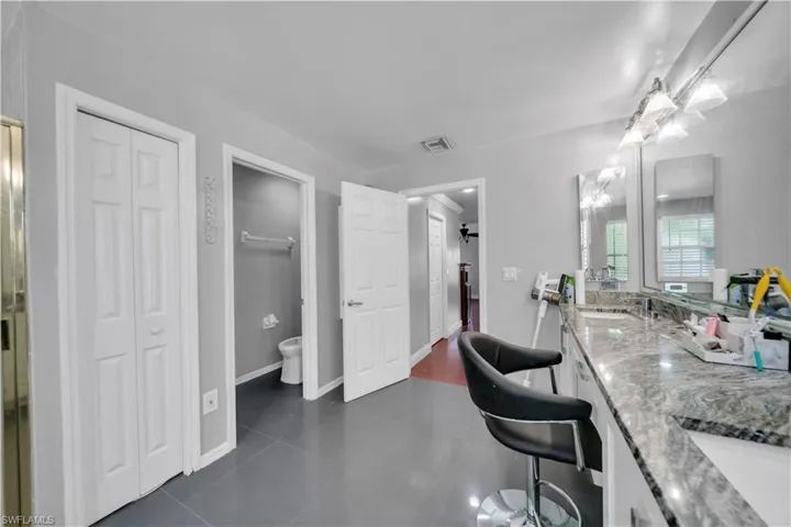 Bathroom featuring a closet, double vanity, toilet, and tile patterned floors