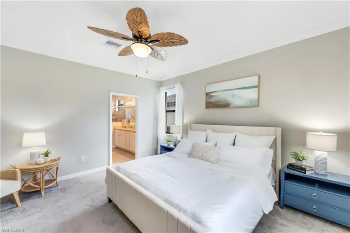 Bedroom featuring ceiling fan, connected bathroom, light carpet, and ornamental molding