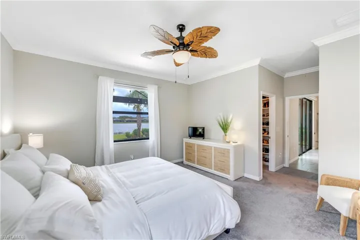Bedroom featuring a spacious closet, carpet, a closet, crown molding, and ceiling fan