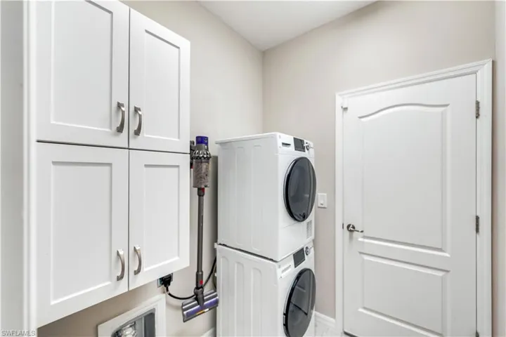 Washroom featuring cabinets and stacked washer / dryer