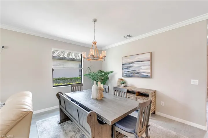 Dining space with crown molding, light hardwood / wood-style flooring, and an inviting chandelier