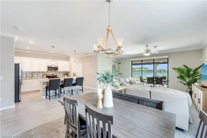 Dining area featuring ceiling fan with notable chandelier, ornamental molding, and light hardwood / wood-style flooring