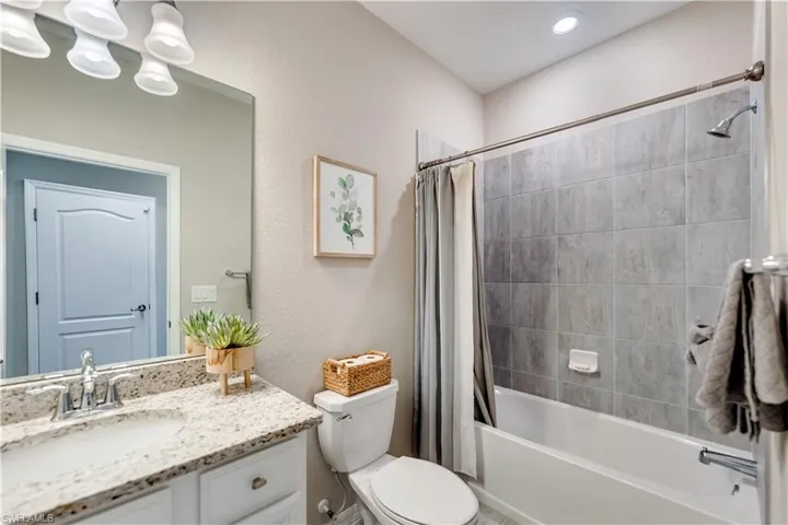 Full bathroom featuring shower / bathtub combination with curtain, toilet, and vanity