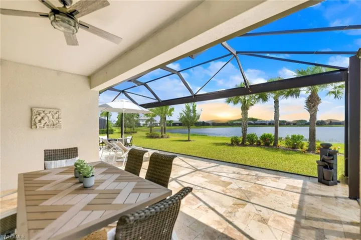 Lanai at dawn with a water view, a yard, and ceiling fan