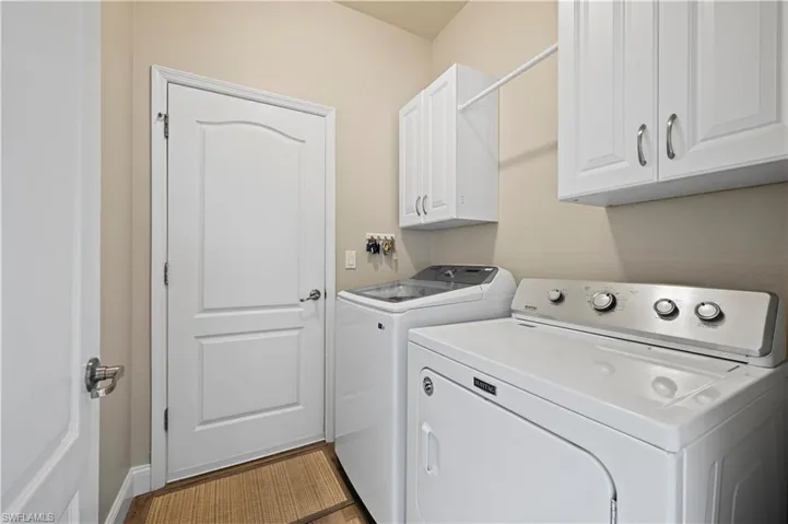 Laundry area with independent washer and dryer, cabinets, and light hardwood / wood-style floors