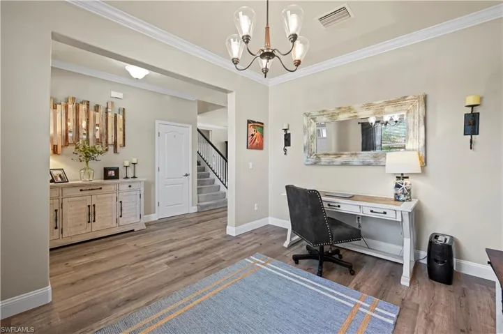 Home office with a notable chandelier, hardwood / wood-style flooring, and crown molding